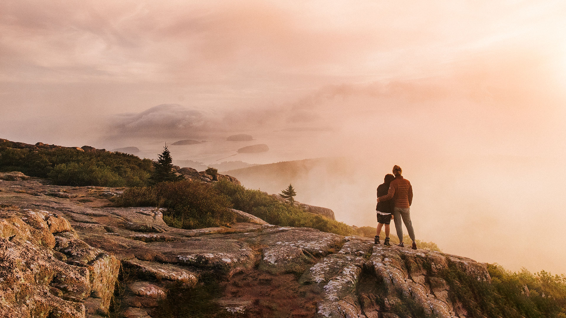 Mother and son stand at the summit of Cadillac Mountain at sunrise