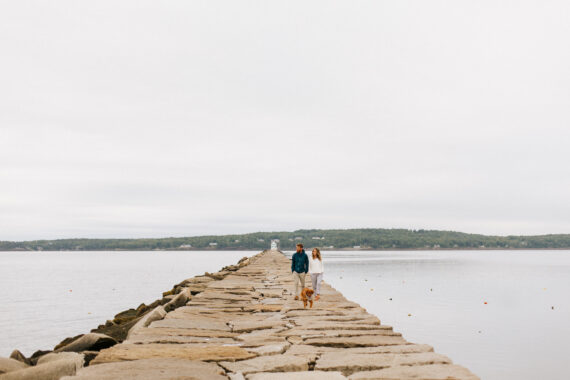 couple walking on a pier with their dog