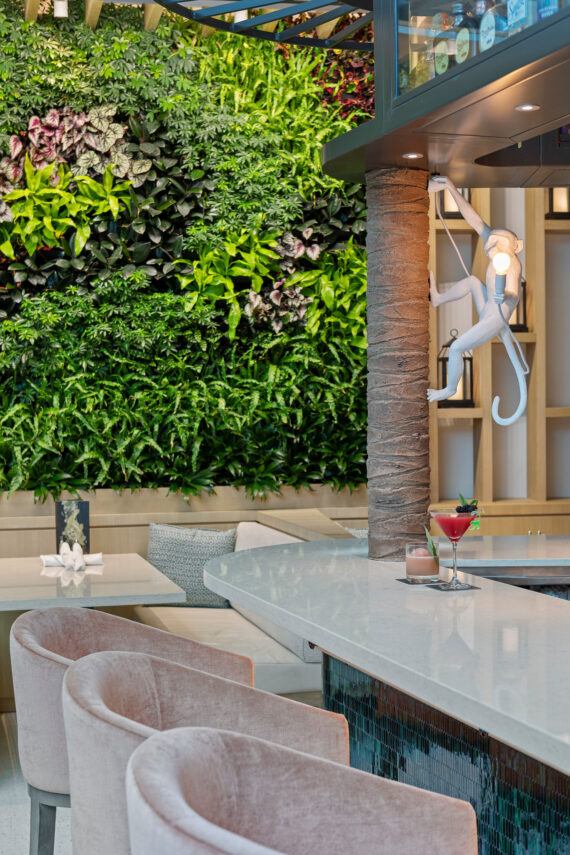 Plush chairs pulled up to a bar with a living wall in the background